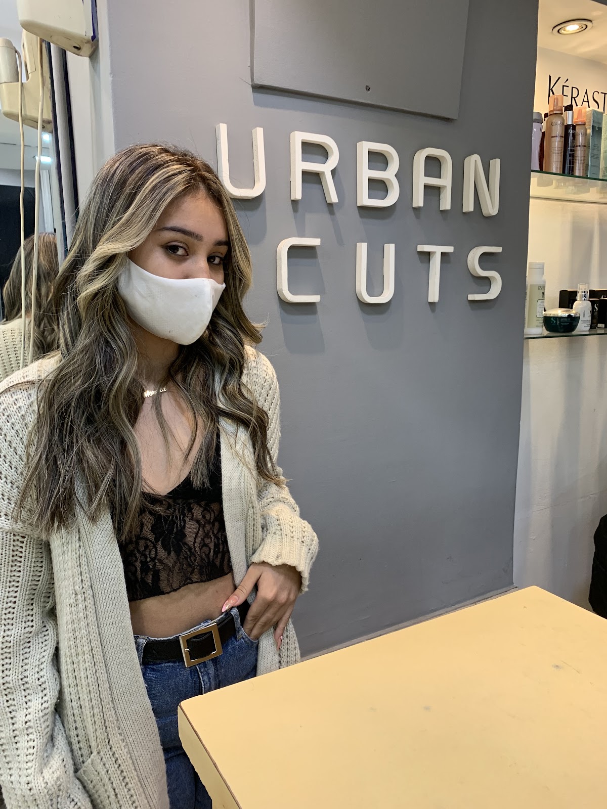Clienta con balayage recién hecho frente al cartel de Urban Cuts en el salón de Almagro